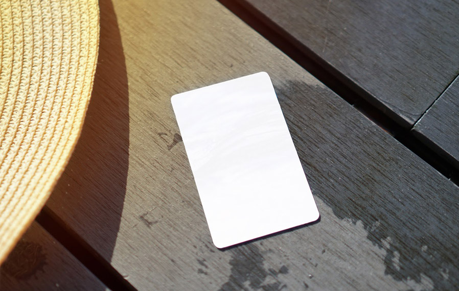 Don't forget your pool pass to to take a refreshing swim at Spark Apartments. Summer hat and key card on a deck floor.