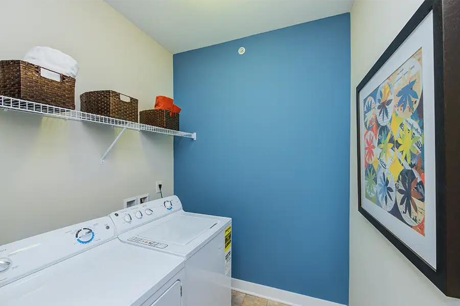 A laundry room or closet like this one at One One Six Apartments is a good place to keep your emergency kit. An in-unit apartment laundry room with laundry machines and a shelf