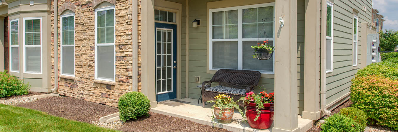 First-floor level corner patio with a bench and flowers. Located at One One Six Apartments.