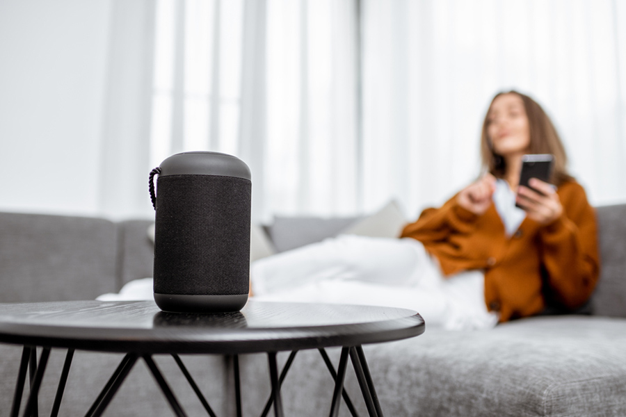 Woman sitting on a sofa beside a smart speaker on a coffee table